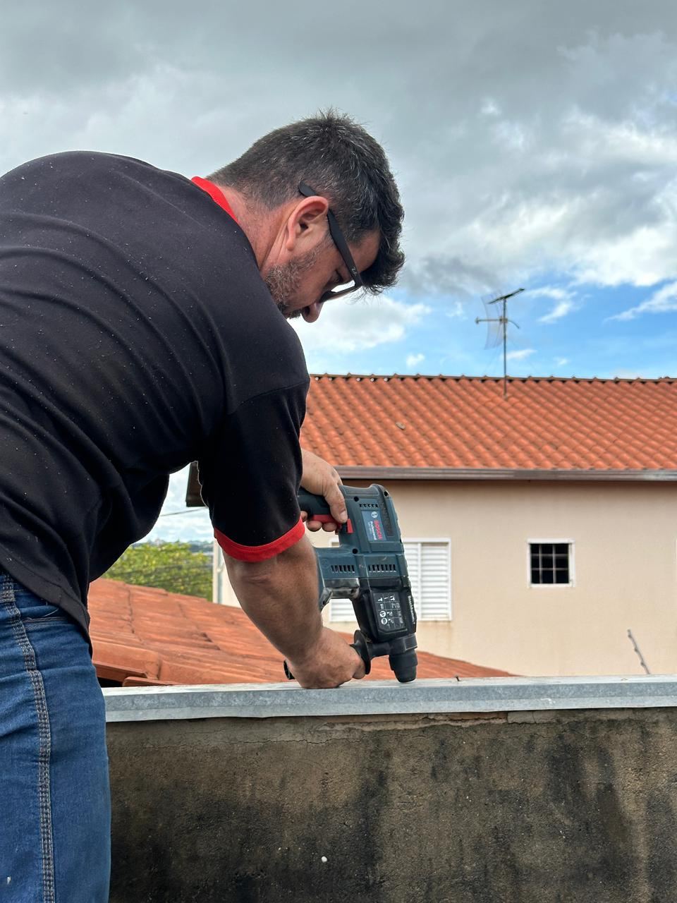 Profissional furando rufo metálico em telhado residencial